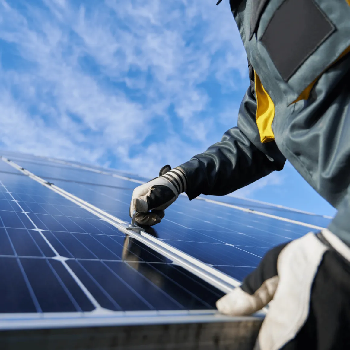 Elektriker montiert ein Solarmodul auf dem Dach